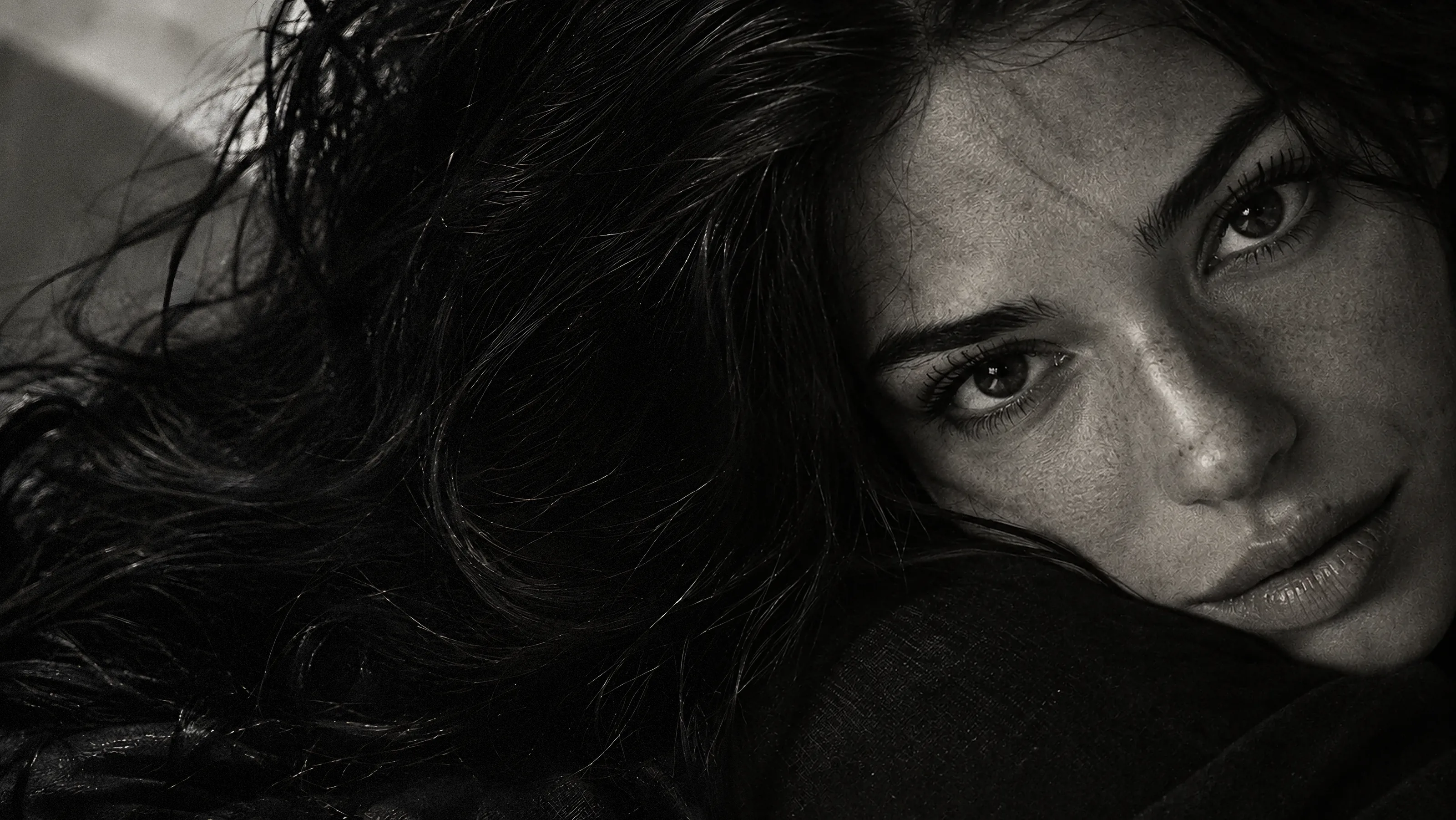 Retrato en blanco y negro de una mujer recostada, mirando a cámara